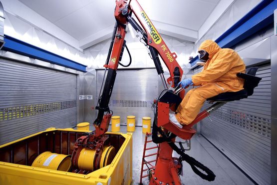 An employee assembles a transport container with waste containers in the interim storage facility Karlsruhe.