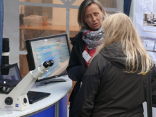 Infostand mit Mikroskop, Mitarbeiterin im Gespräch mit Besucherin