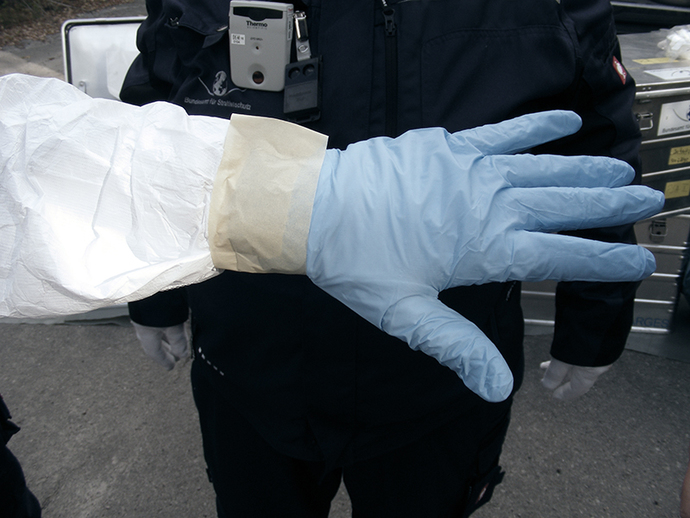 Der Handschuh wird am Schutzanzug festgeklebt
