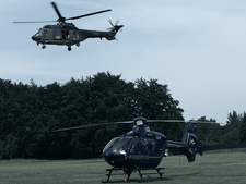 Two helicopters landing on grassland