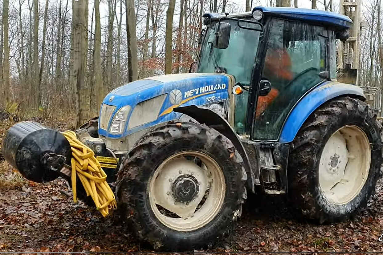 Das Vorschaubild des YouTube-Videos zeigt einen blauen Traktor in einer Waldumgebung.