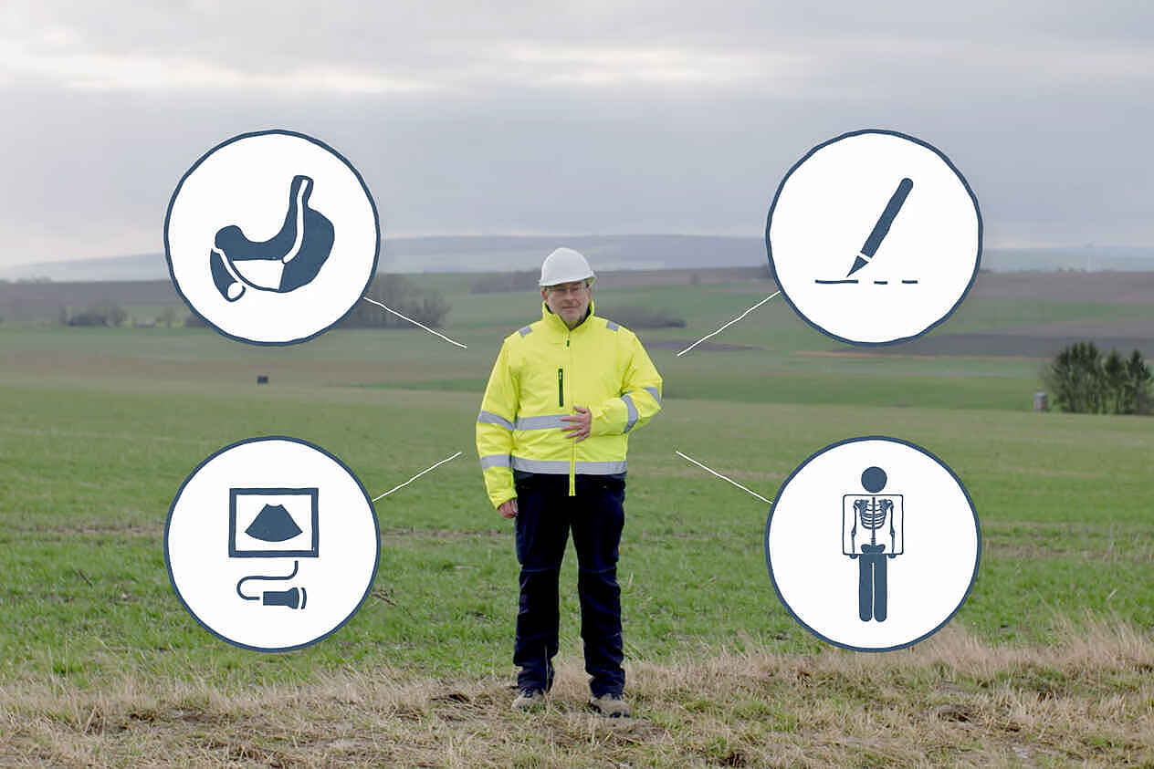 Eine Person mit weißem Schutzhelm und neongelber Arbeitsjacke steht auf einem Feld. Mit einer Hand hält sich die Person ihren Bauch. Links und rechts neben der Person sind vier runde Piktogramme eingeblendet, die einen Magen, einen Stift, einen Monitor und eine von Röntgenstrahlen durchleuchtete Person schematisch darstellen.