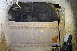 In einer unterirdischen Strecke befindet sich eine schwarze Wand, vor der wiederum eine halbhohe Betonwand steht. 