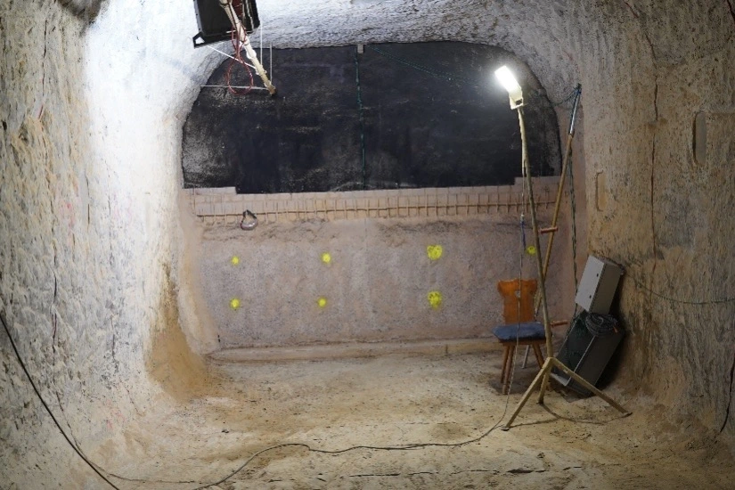 Das Bild zeigt eine Frontalansicht auf das Bauwerk. Zu sehen ist eine halbhohe Mauer, hinter der das Bitumenschott entsteht.