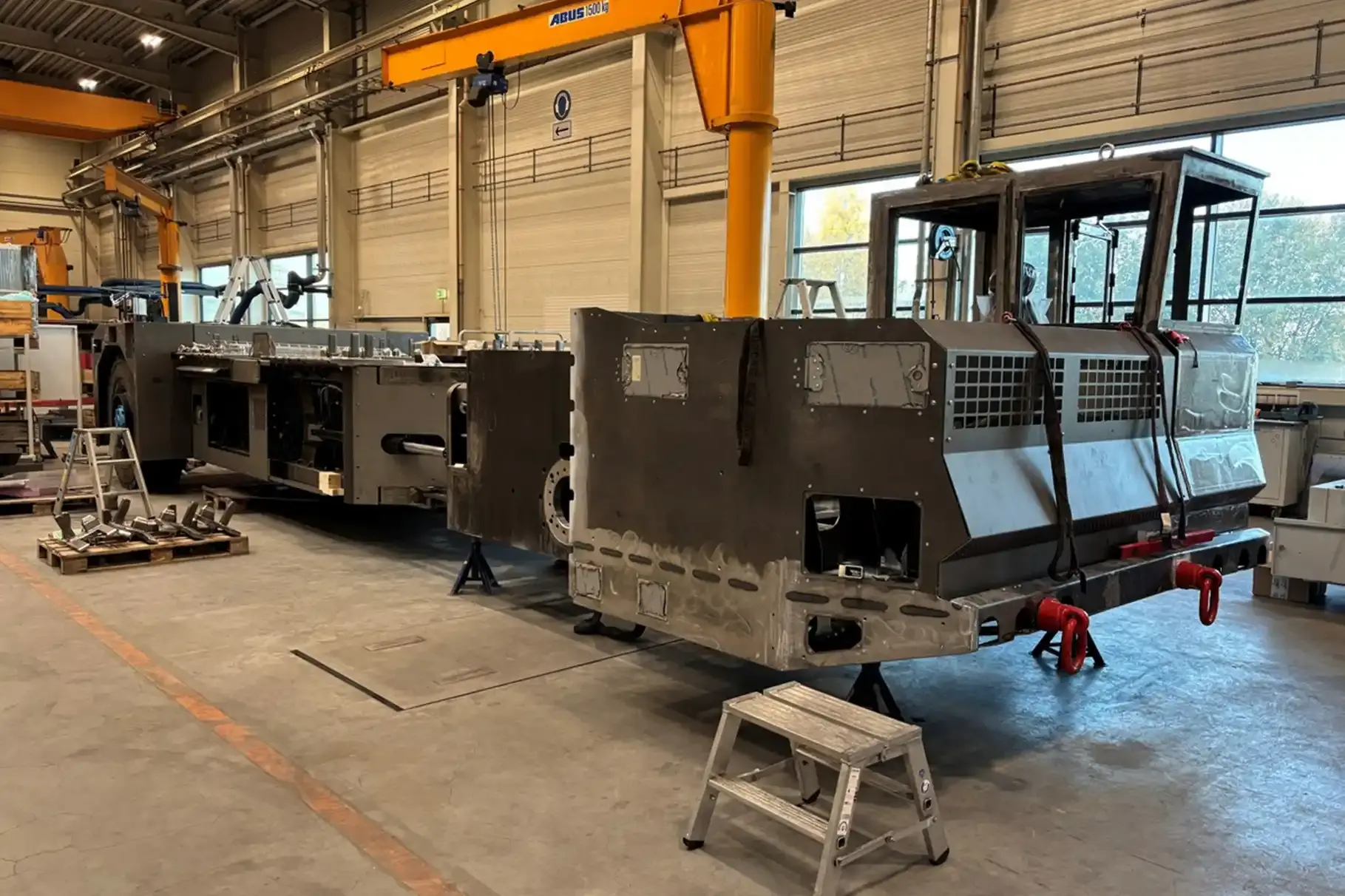 Ein großes Transportfahrzeug im Rohbau steht in einer Werkshalle.