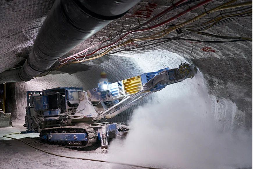 Das Foto zeigt eine Maschine in einem Bergwerk, die mit einem Fräskopf Salzgestein abträgt. 