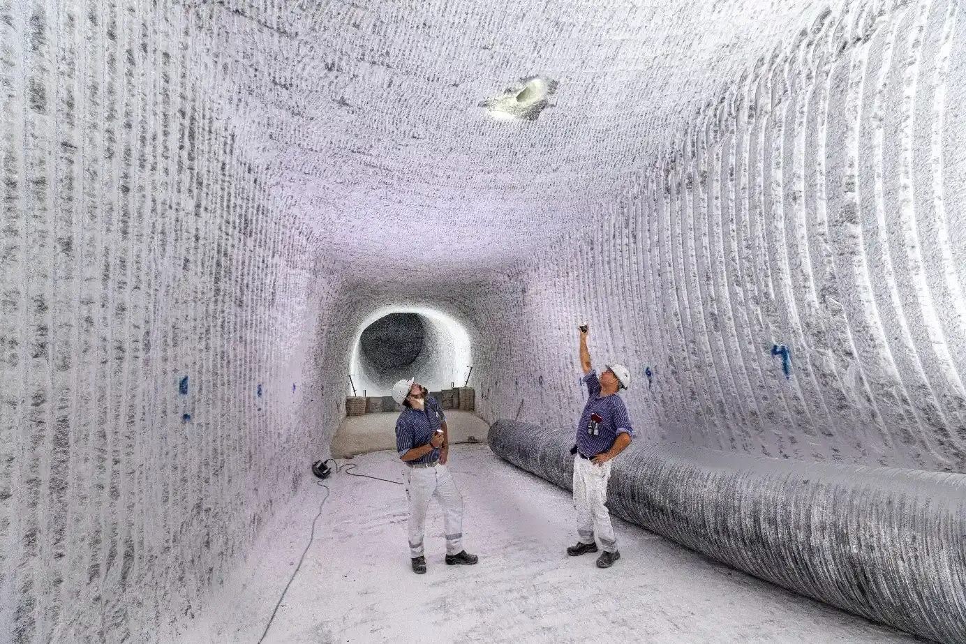 Zwei Bergleute stehen in einem Gang unter Tage.