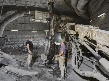 Vorbereitung für die Errichtung der Versatzaufbereitungsanlage Two miners drill holes in the ground with a large machine for rock bolts