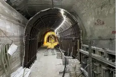 Foto einer halbrunden Gitterstruktur in einem Bergwerk unter Tage. Vor der Gitterstruktur befinden sich gebogene Metallträger. Gemeinsam erzeugt die Konstruktion den Eindruck eines Tunnels unter Tage.