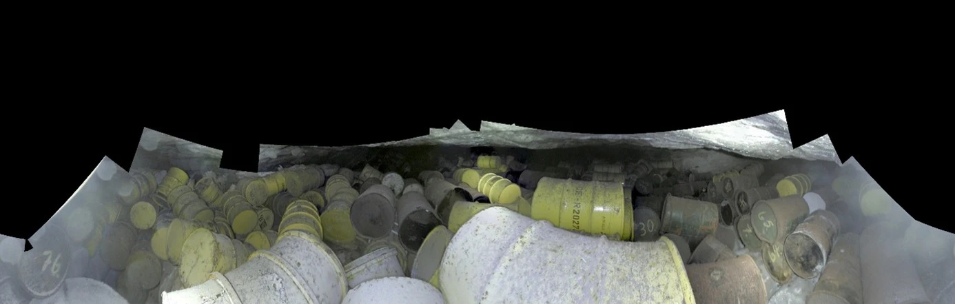 Panoramafoto von gelben, teilweise mit Staub bedeckten Fässern in einem Bergwerk. 