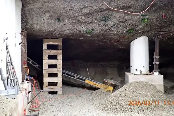 Mit Betonstützen und provisorischen Holzstützen sichern die Bergleute die Kammerdecke ab, um sich weiter bis zum Ende der Kammer vorabreiten zu können. Die Kammer endet an einer gut sichtbaren Kluft. 