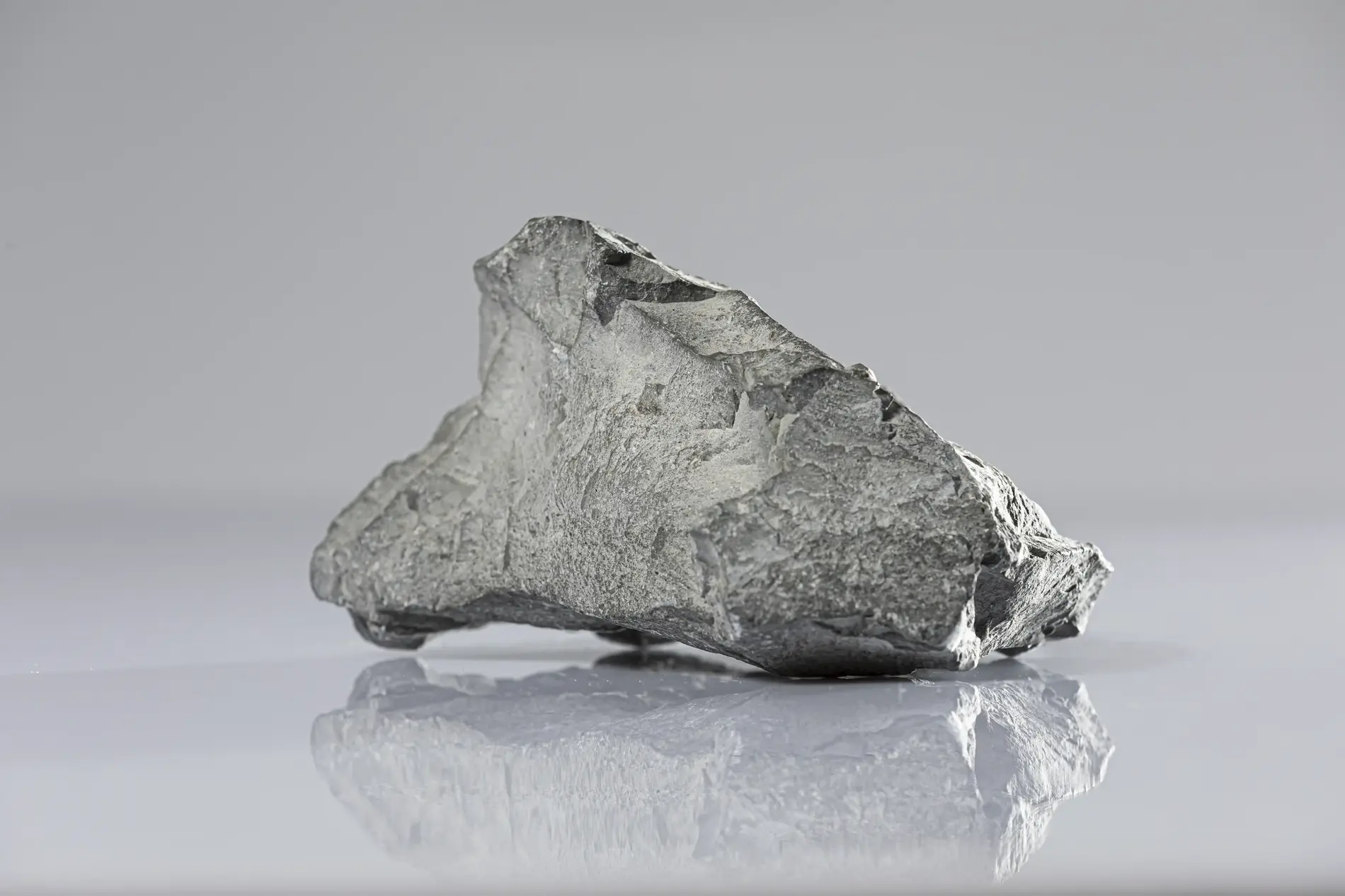 A gray lump of rock lies on a table, slightly reflected in its smooth surface.