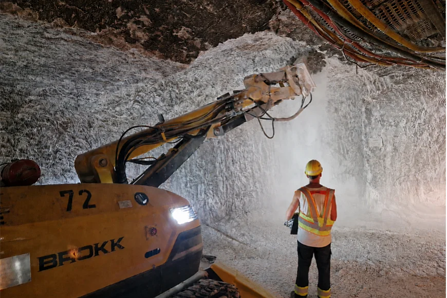 Das Foto zeigt eine Maschine in einem Bergwerk, die mit einem Fräskopf Salzgestein abträgt. 