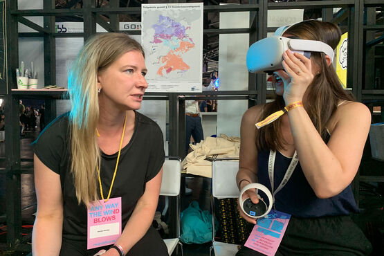 Zwei Frauen sitzen nebeneinander, eine trägt eine VR-Brille.