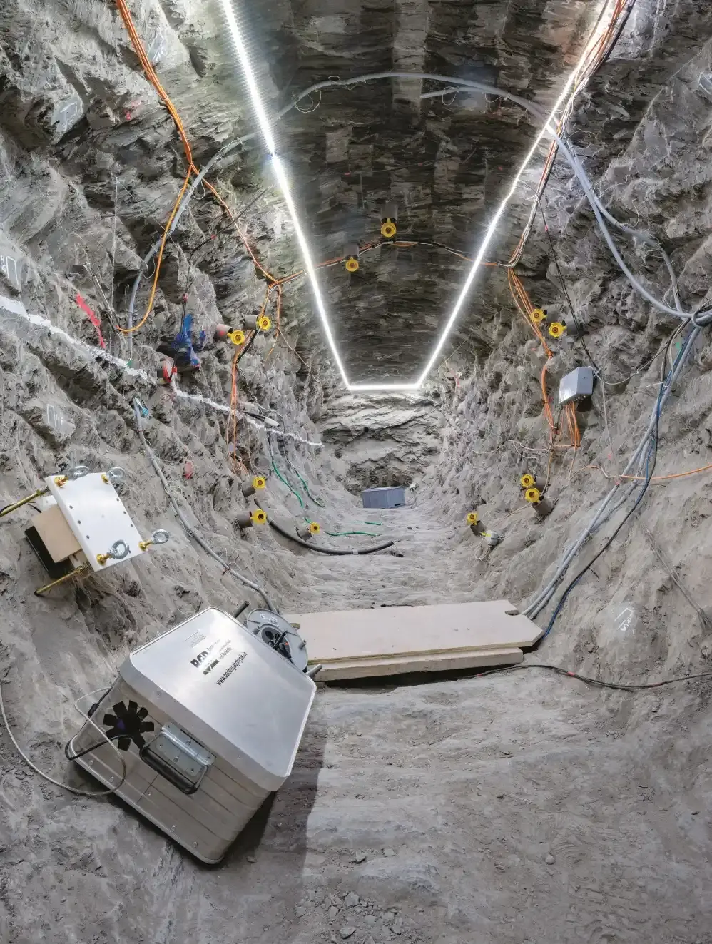 Blick auf Gestein, in dem zahlreiche Messinstrumente verankert sind, die mit Kabeln verbunden sind.