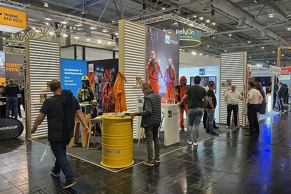 Auf dem Bild ist der Messestand der BGE auf der Interschutz zu sehen. Personen stehen auf dem Stand und unterhalten sich.