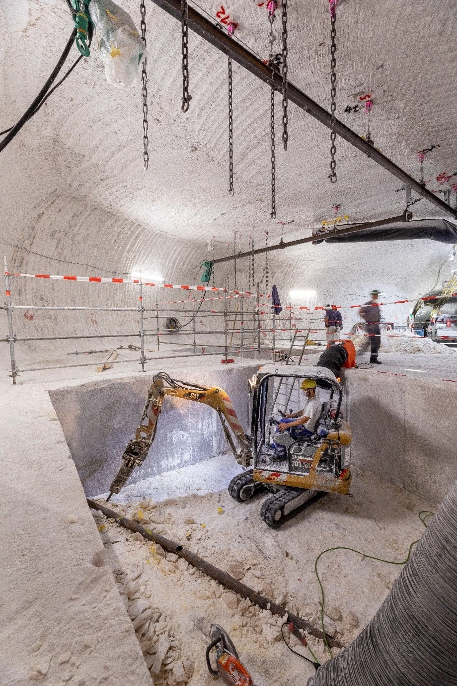 Ein Bagger und Bergleute in einem Bohrkeller unter Tage.
