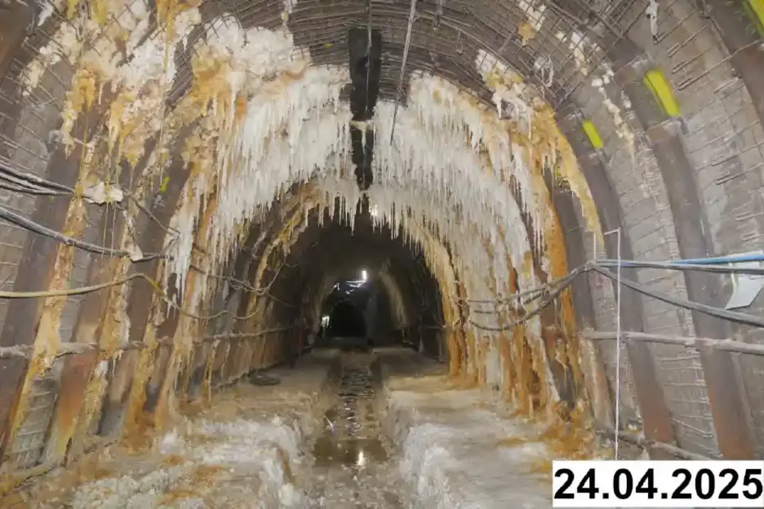 Foto einer bogenförmigen Strecke unter Tage. An den Seiten und der Decke bilden sich weiße Verkrustungen.