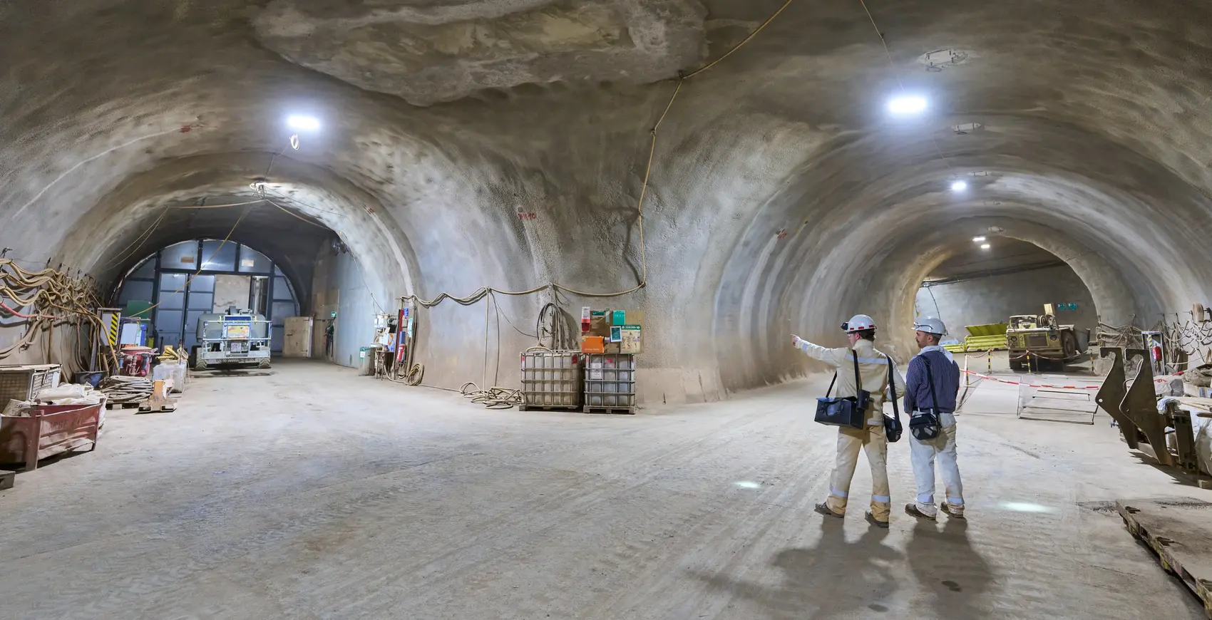 	Zwei Personen stehen in Bergmannskluft in einem unterirdischen Tunnel.