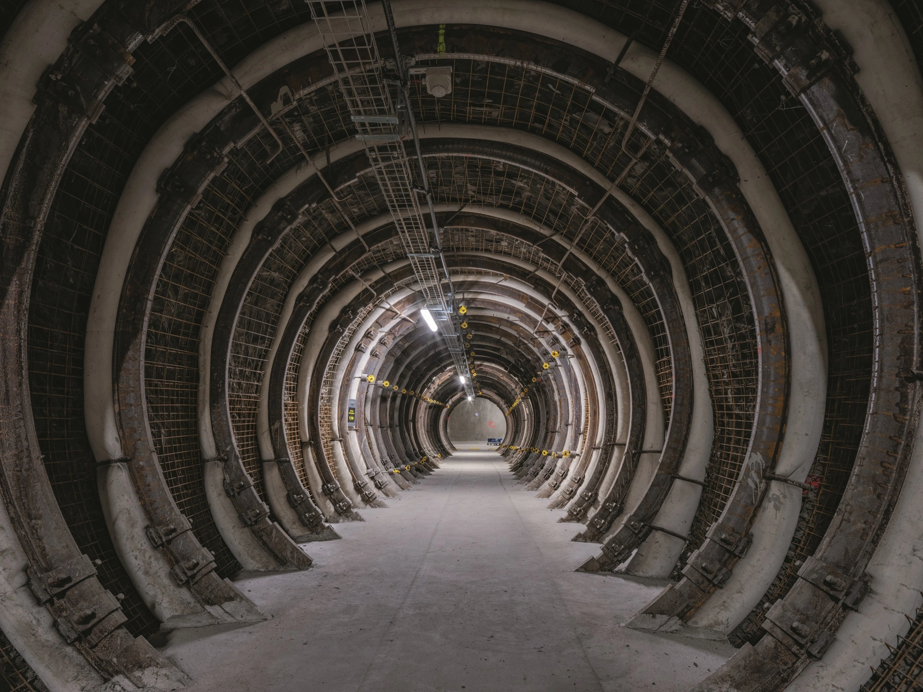 Blick in eine beleuchtete Strecke unter Tage, die aussieht wie ein Tunnel mit Metallkonstruktionen an den Wänden.