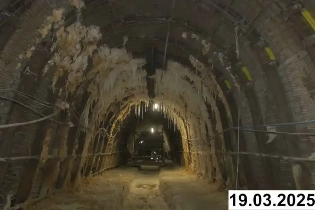 Foto einer bogenförmigen Strecke unter Tage. An den Seiten und der Decke bilden sich weiße Verkrustungen.