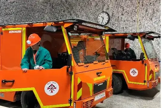 Eine Person steigt aus einem kleinen orangenen Löschfahrzeug. Im Hintergrund steht ein zweites Fahrzeug. 