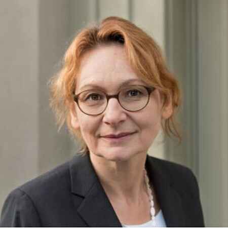 Portraitfoto einer Frau im schwarzen Blazer, Brille und roten Haaren.