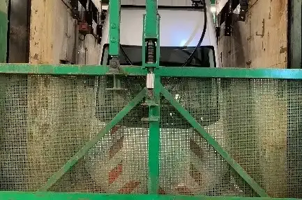 3.	Die Oberseite eines kopfüber hängenden Fahrzeugs ist zu sehen. Davor hängt ein grünes Gittertor. 