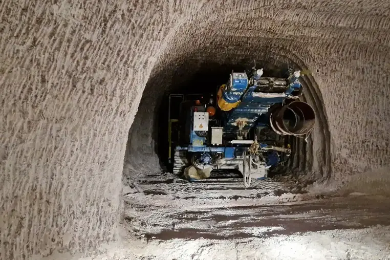 Das Bild zeigt eine große Fräsmaschine in einer in das Steinsalz geschnittenen Nische. An den Wänden und der Decke sind typische, wellenartige Frässpuren im Steinsalz zu erkennen. Auf dem Boden liegt loses Salz.