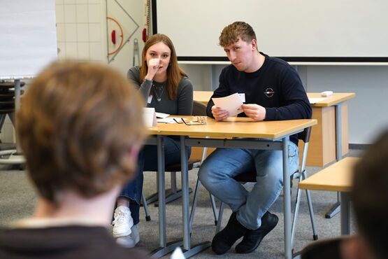 Eine Schülerin und ein Schüler der Berufsbildenden Schulen II in Gifhorn schauen konzentriert einen Mitschüler an, der seine Position im Planspiel deutlich macht.