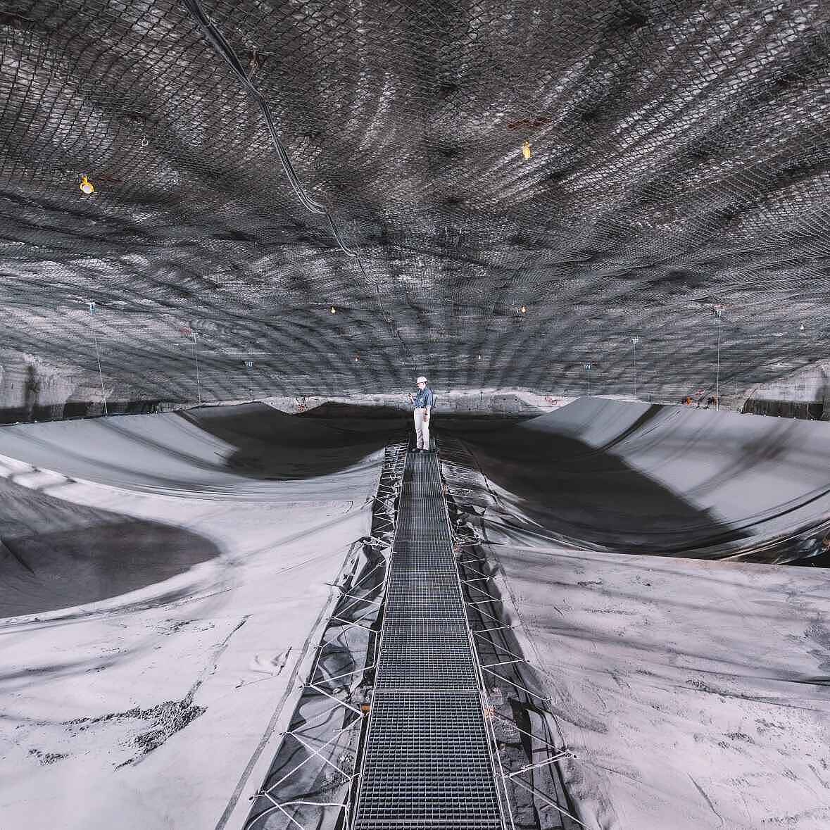 Speicherbecken unter Tage, das mit Planen abgedeckt ist. Auf einem Arbeitssteg in der Bildmitte steht im Hintergrund eine Person in Arbeitskleidung und Helm.