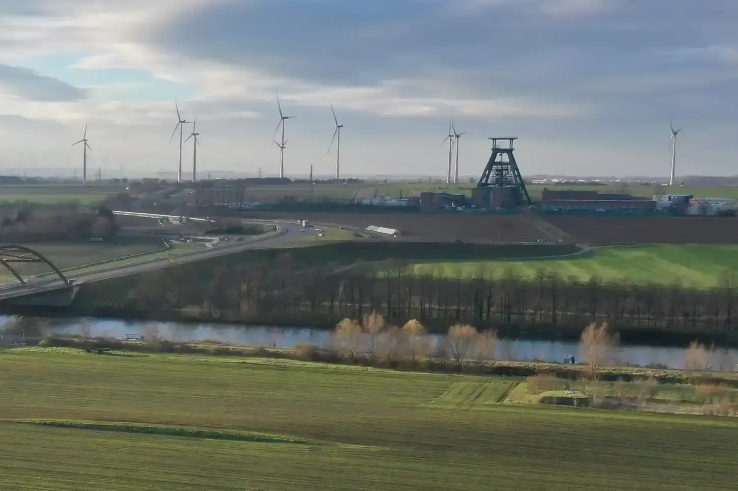 Endlager Konrad aus der Luft Luftaufnahme: Vor leicht bewölktem Himmel und zahlreichen Windrädern am Horizint ist die Schachtanlage 1 des Endlagers Konrad mit ihrem markanten Förderturm zu sehen. Im Vordergrund verläuft der Salzgitter Stichkanal. Darüber führt eine Autobrücke.
