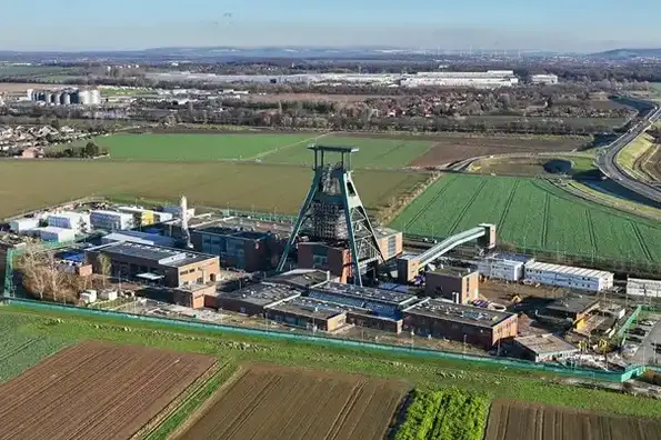 Die Luftaufnahme der Schachtanlage Konrad 1 zeigt ein Industriegelände mit Gebäuden und Förderturm inmitten von Feldern.