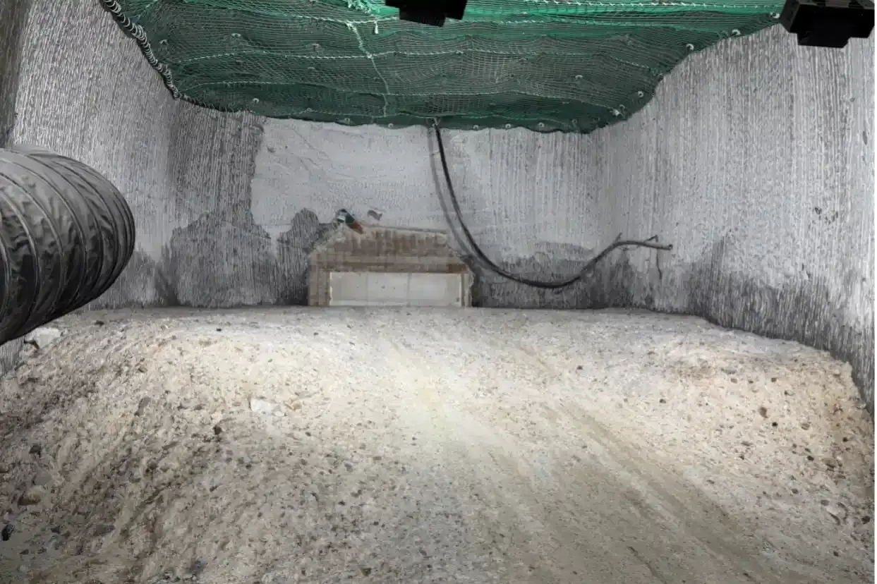 In einer Nische unter Tage befindet sich ein Haufen loses Salz. Über die Decke ist ein grünes Netz gespannt. 