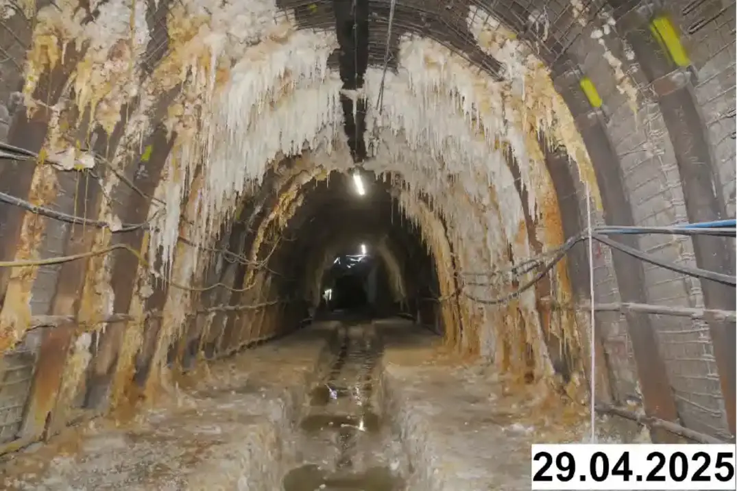 Foto einer bogenförmigen Strecke unter Tage. An den Seiten und der Decke bilden sich weiße Verkrustungen.