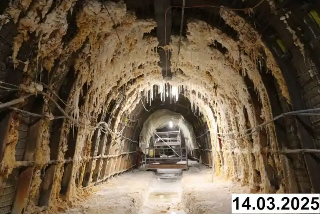 Foto einer bogenförmigen Strecke unter Tage. An den Seiten und der Decke bilden sich weiße Verkrustungen.
