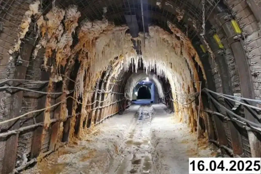 Foto einer bogenförmigen Strecke unter Tage. An den Seiten und der Decke bilden sich weiße Verkrustungen.