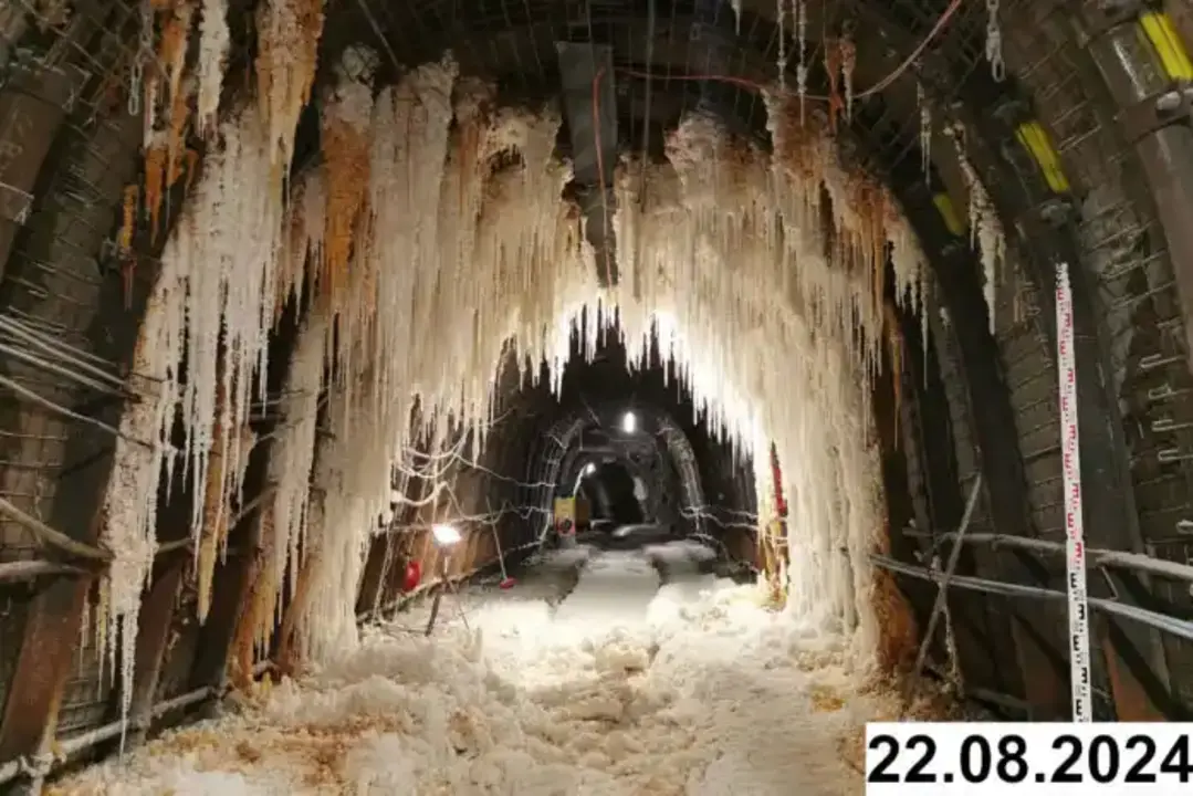 Foto einer bogenförmigen Strecke unter Tage. An den Seiten und der Decke bilden sich weiße Verkrustungen.