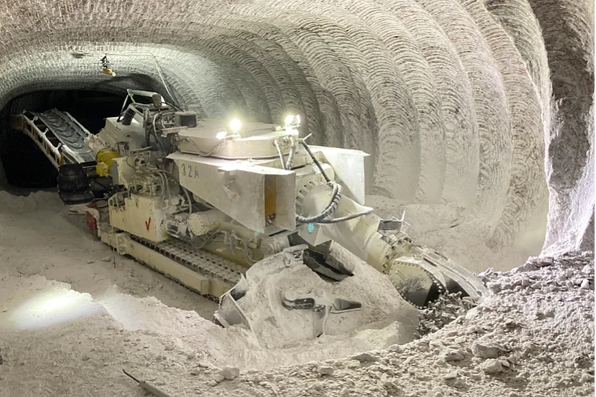 Das Foto zeigt eine Maschine in einem Bergwerk, die mit einem Fräskopf Salzgestein abträgt. 