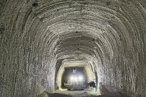 Enie Strecke in einem Bergwerk. Am Ende steht ein beleuchtetes Fahrzeug.