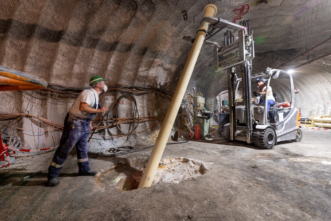 Bergleute verlegen unter Tage ein Rohr in den Boden.
