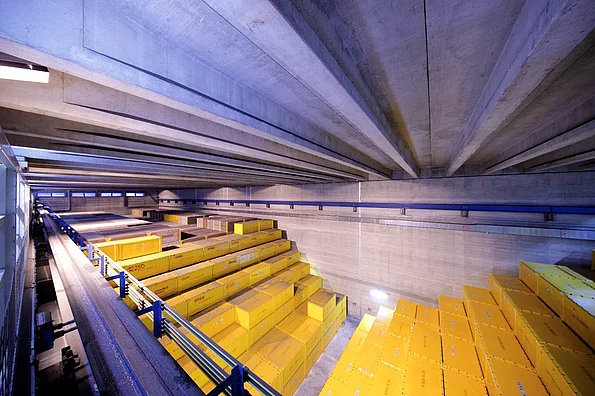 Blick in eine große Lagerhalle des Zwischenlagers Karlsruhe mit großen gelben Containern, die aufeinander gestapelt sind.