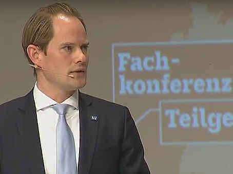 BGE-Geschäftsführer Steffen Kanitz bei der Auftaktveranstaltung zur Fachkonferenz Teilgebiete Ein Mann im Anzug vor dem Logo der Fachkonferenz Teilgebiete