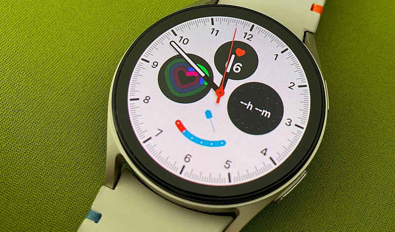 Foto einer Smartwatch mit weißem Ziffernblatt auf grünem Untergrund.