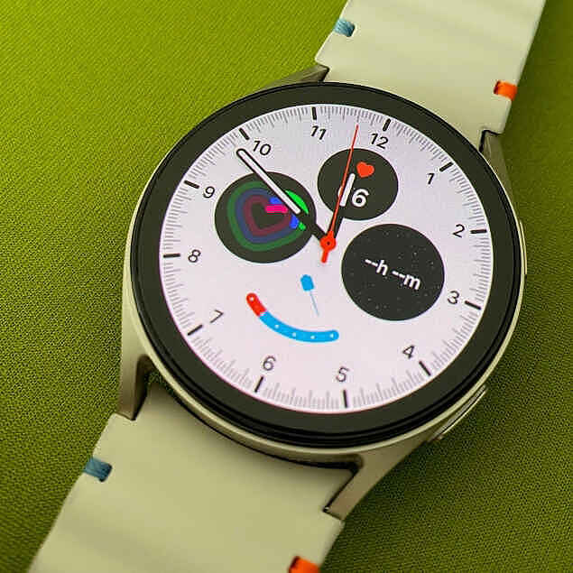 Foto einer Smartwatch mit weißem Ziffernblatt auf grünem Untergrund.