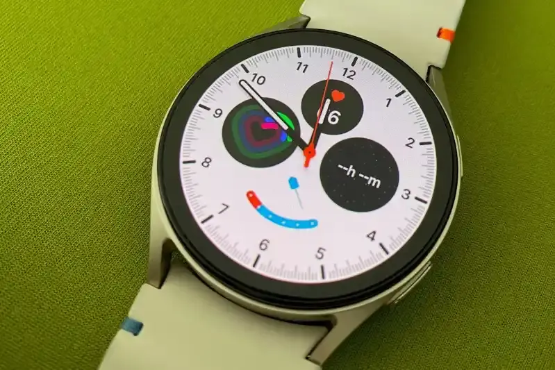 Foto einer Smartwatch mit weißem Ziffernblatt auf grünem Untergrund.
