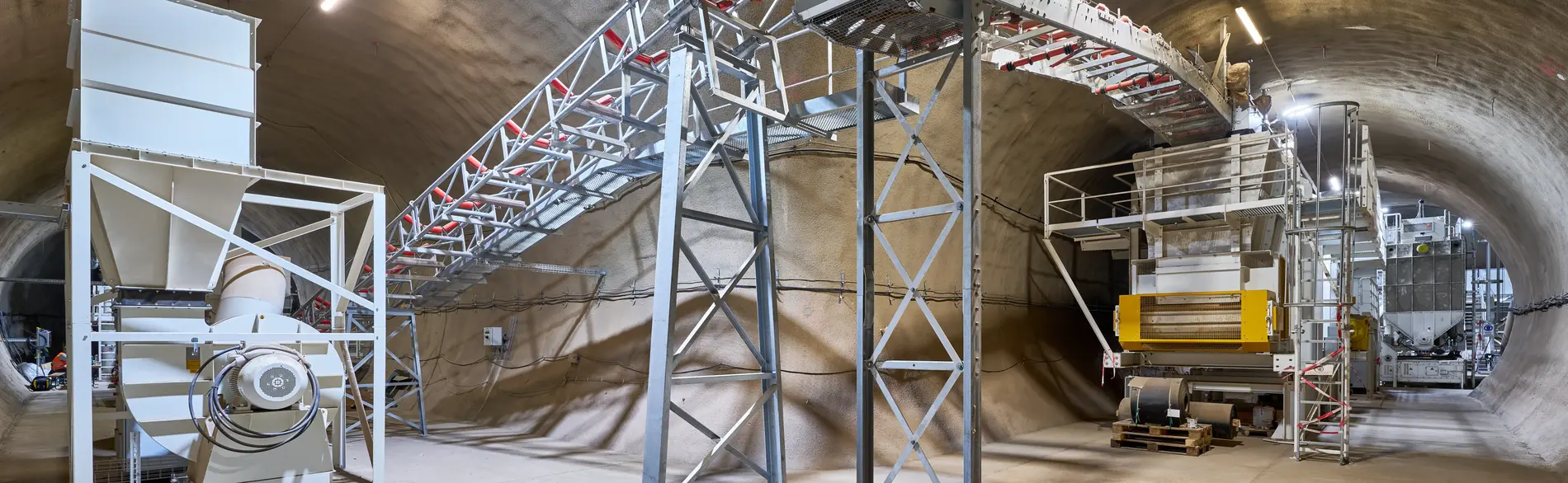 Das Foto zeigt eine unterirdische Industrieanlage im Endlager Konrad mit Förderband, Maschinen und Stahlkonstruktionen.