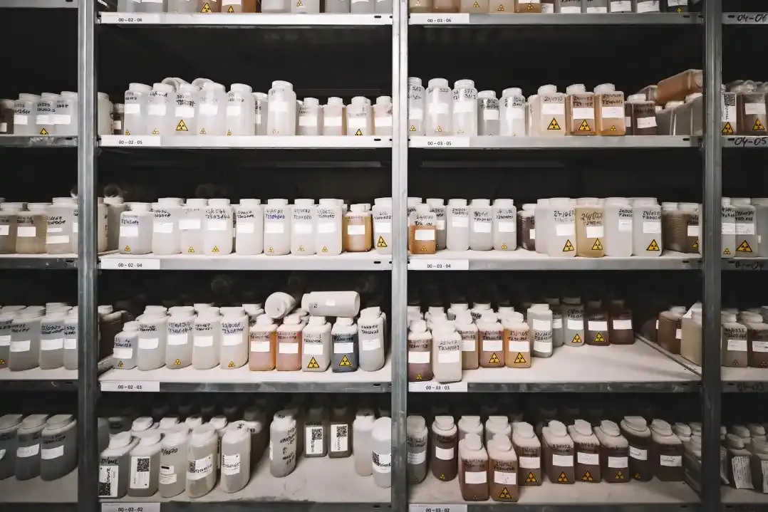 Breites Regal mit mindestens fünf Böden, die mit Probenbehältern gefüllt sind. In den beschrifteten Behältern befinden sich Flüssigkeiten in unterschiedlichen Farben.