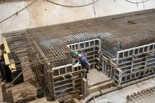 Arbeiten in einer Strecke unter Tage im Bergwerk Konrad: Eine Person mit Schutzhelm arbeitet an großen Stahlmatten.