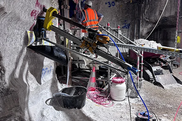 Zu sehen ist ein Arbeitsbereich unter Tage auf der 658-Meter-Sohle im Salzgestein. Im Vordergrund ist eine Bohranlage zu erkennen. Im Hintergrund stehen Menschen und besichtigen den Arbeitsort.